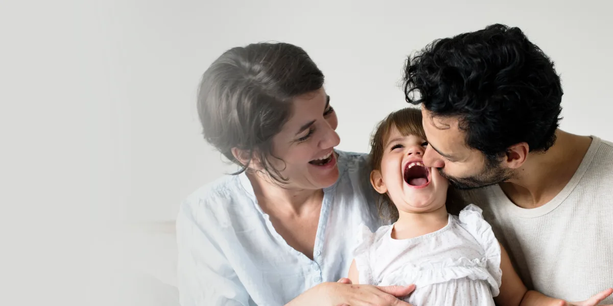 Two parents laughing with their young daughter